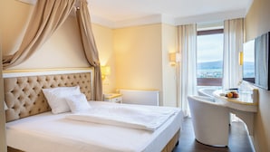 A hotel room with a large bed, a desk with a chair, a window with a view, and a television.