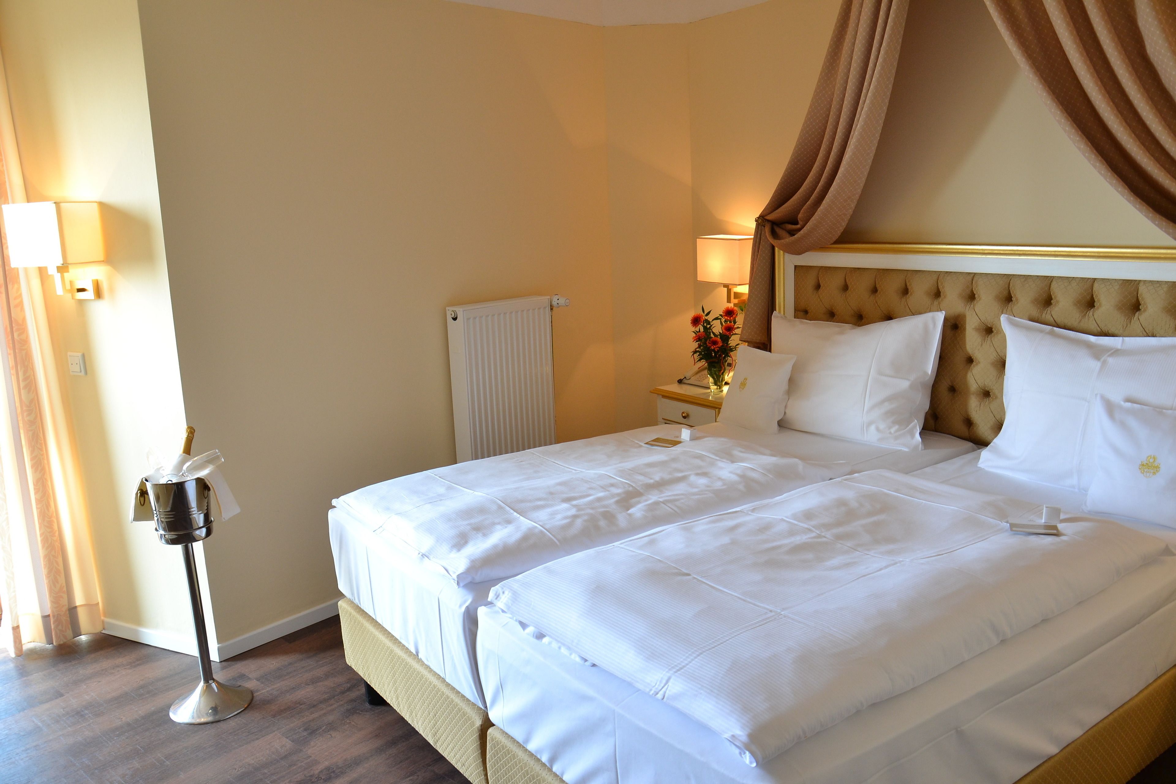 A hotel room with a large bed, a nightstand with a lamp, and a radiator.