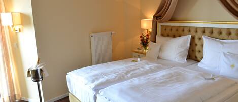 A hotel room with a large bed, a nightstand with a lamp, and a radiator.