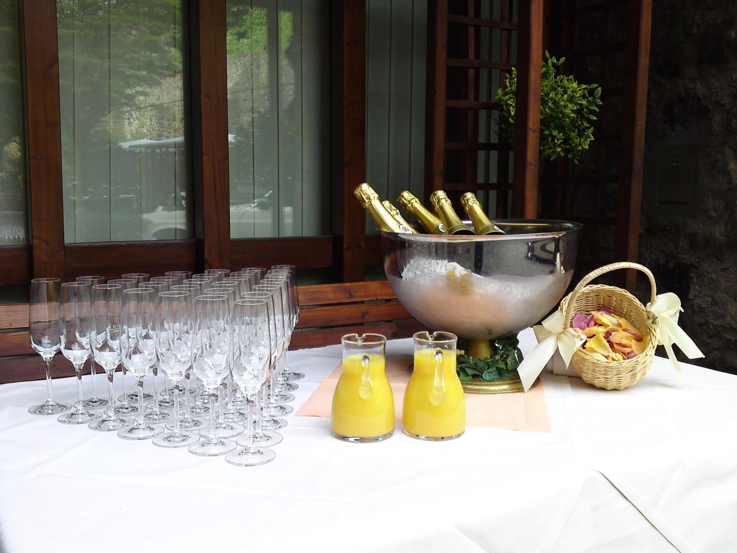 A table set with multiple wine glasses, a bucket with champagne bottles, and two glasses of orange juice.