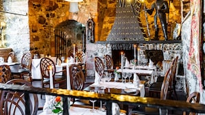 A restaurant with stone walls, wooden tables, and chairs.