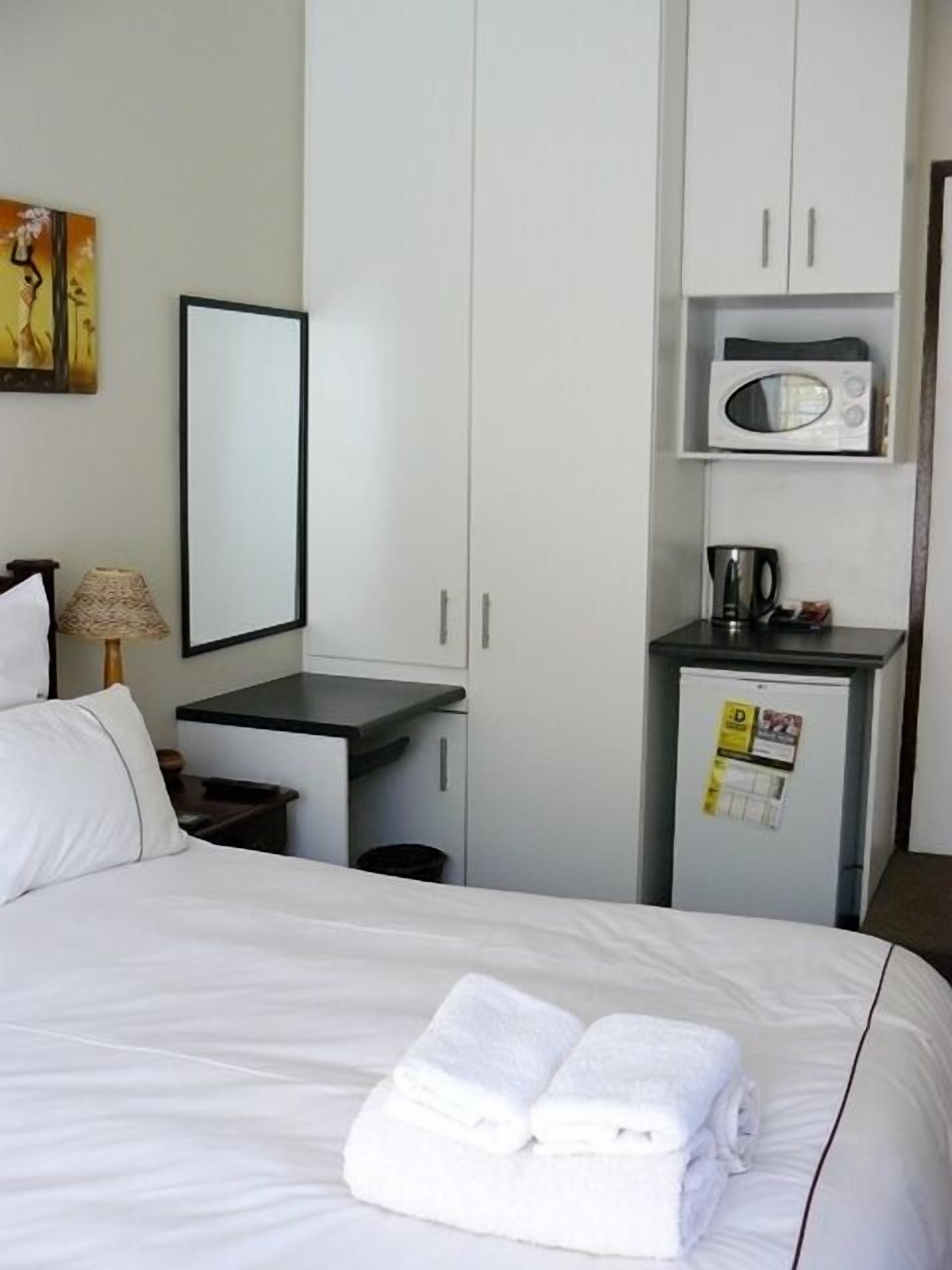 A hotel room with a bed, a desk, a microwave, and a small refrigerator.