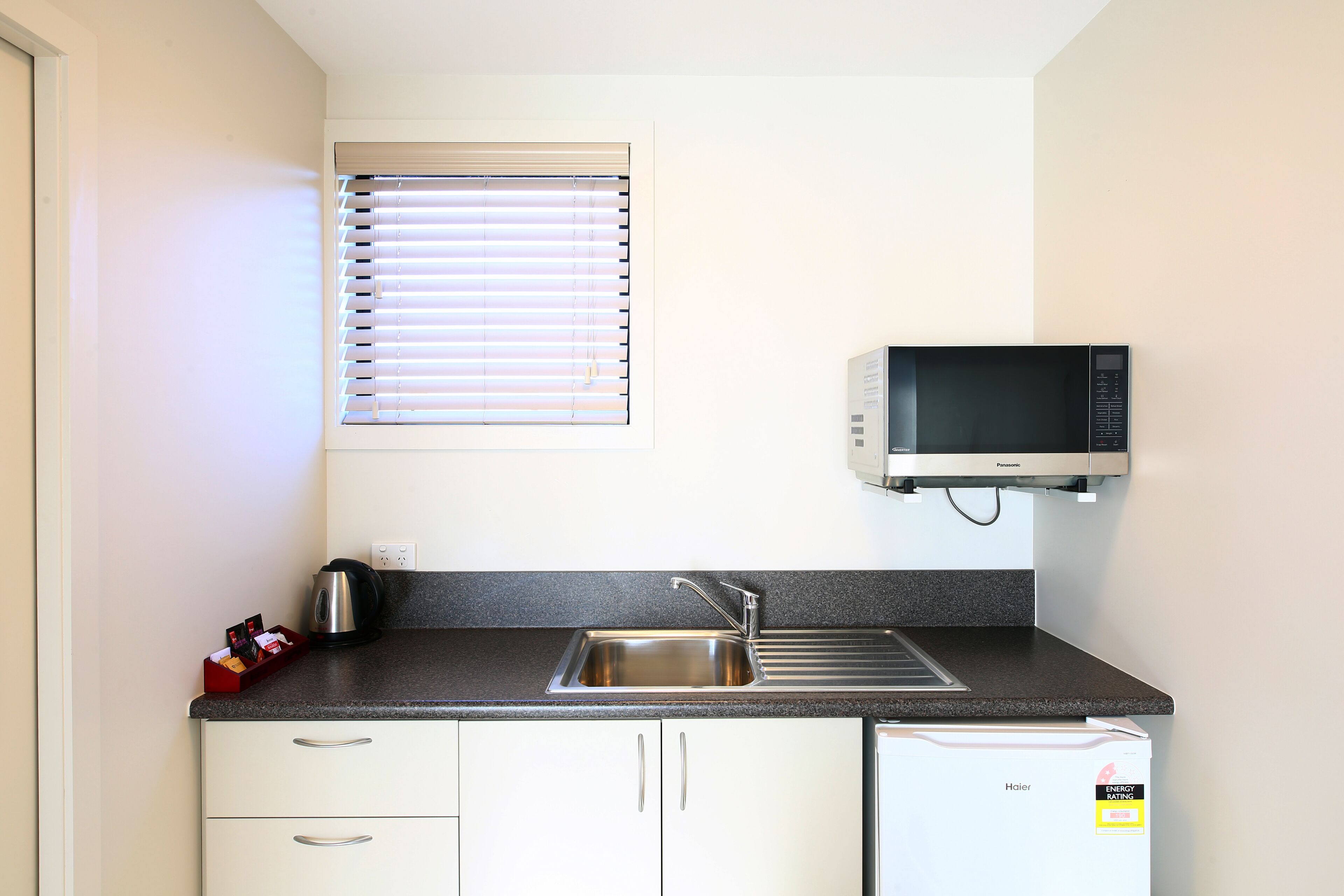 A compact kitchen with a built-in microwave, a stainless steel sink, and a dishwasher.