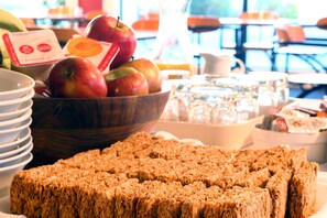 A breakfast buffet with a variety of fruits, including apples and bananas, and a selection of cereals. - Heritage Court Lodge  (Oamaru)