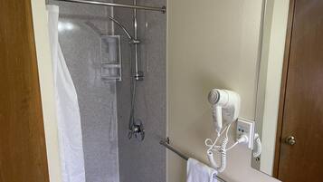 Une salle de bain équipée d’une douche, d’un porte-serviettes et d’un sèche-cheveux fixé au mur.