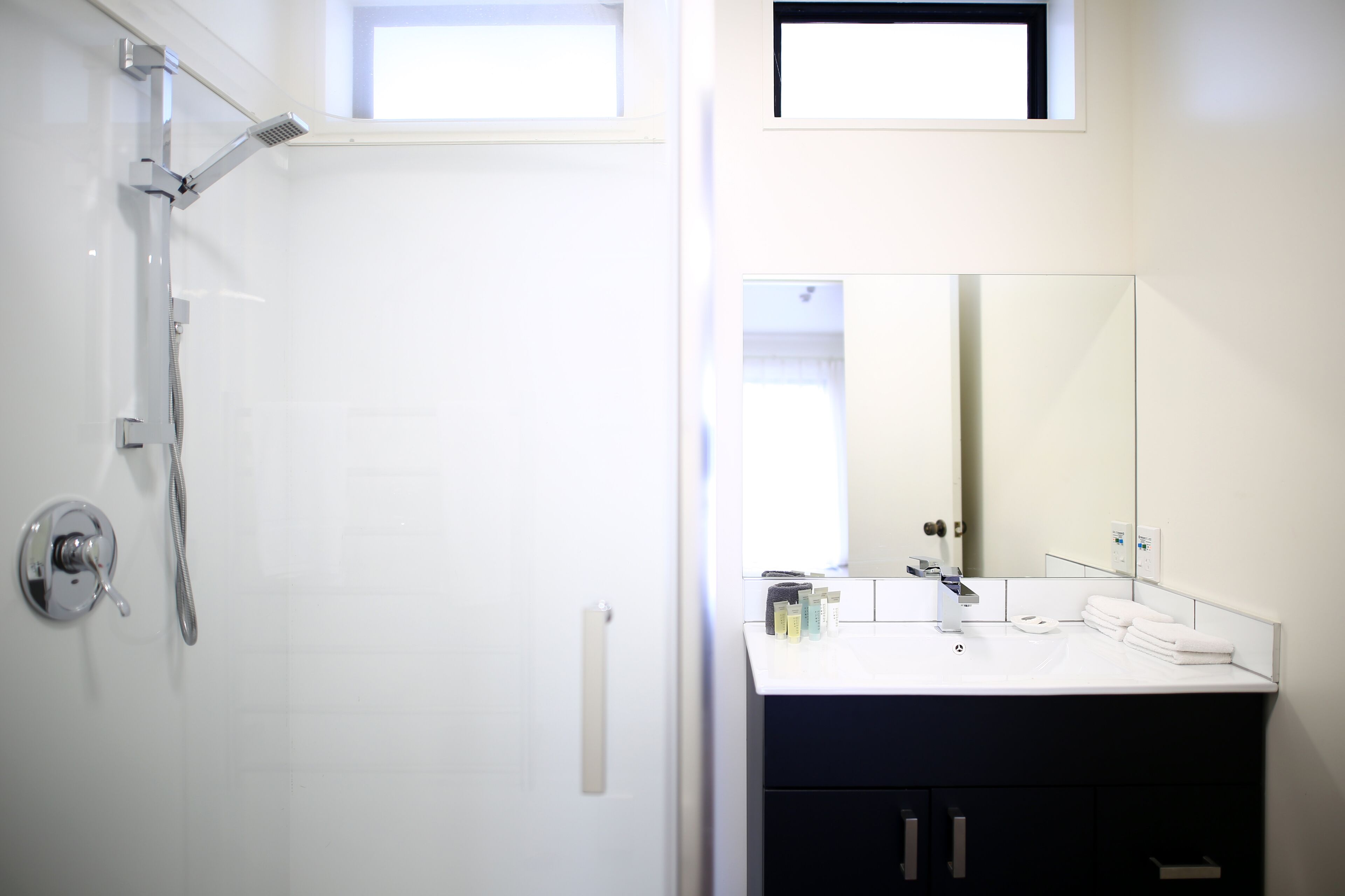 Een moderne badkamer met een douche, een wastafel en een grote spiegel.