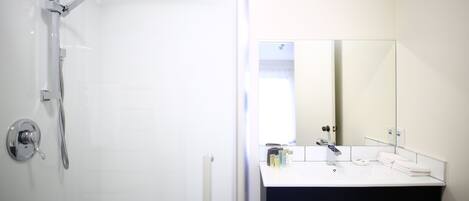 Een moderne badkamer met een douche, een wastafel en een grote spiegel.