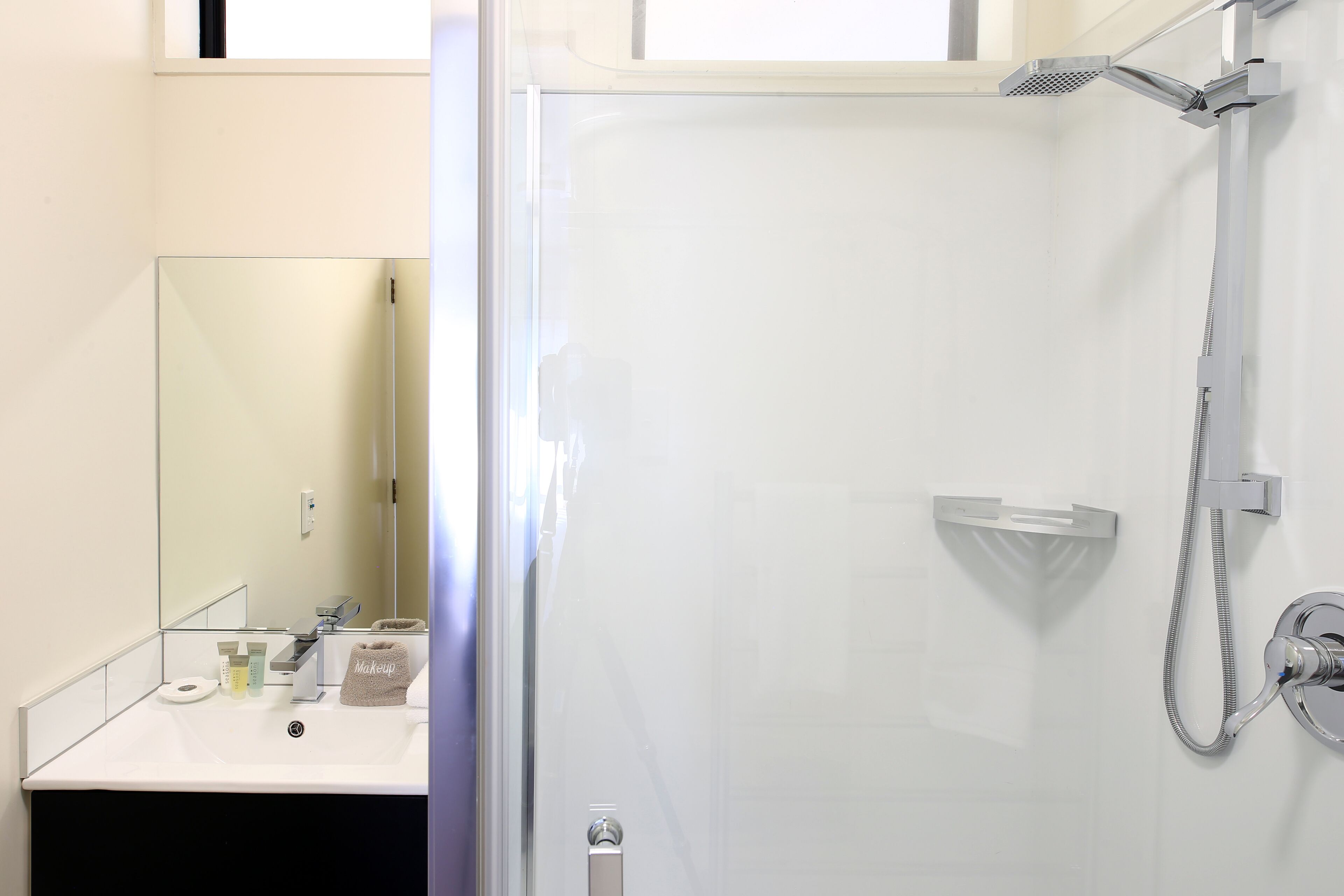 A modern bathroom with a glass shower enclosure, a white sink, and a large mirror.