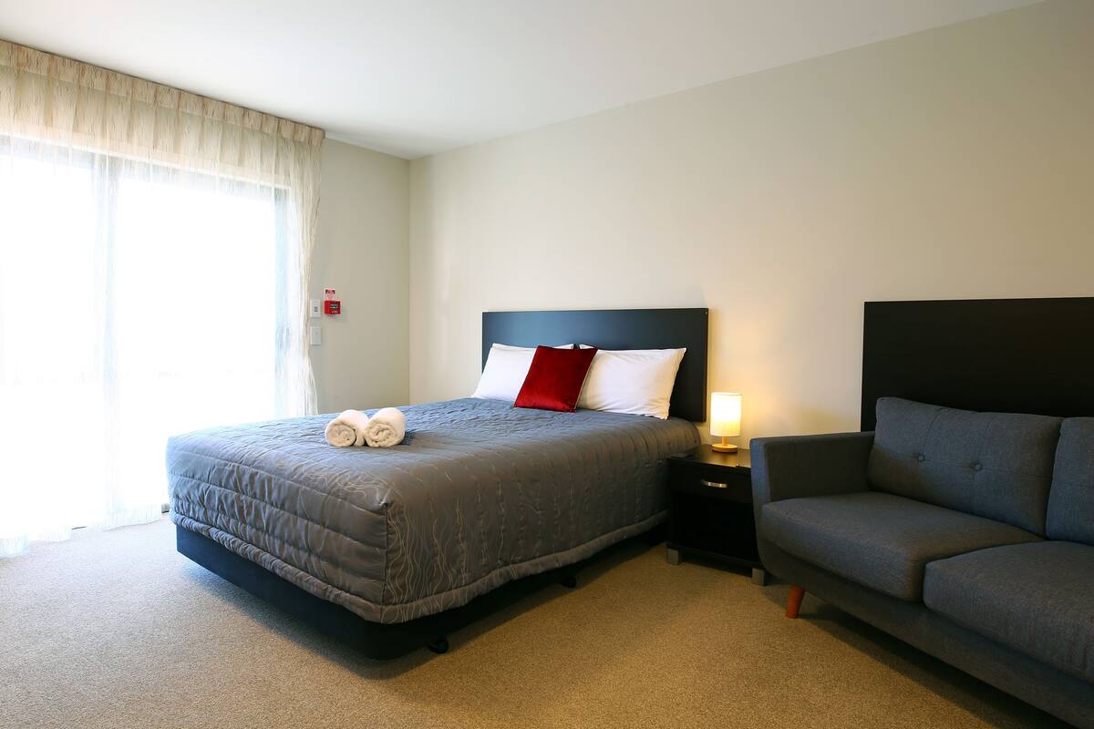 Ein Hotelzimmer mit Bett, Sofa, Nachttisch und Lampe.