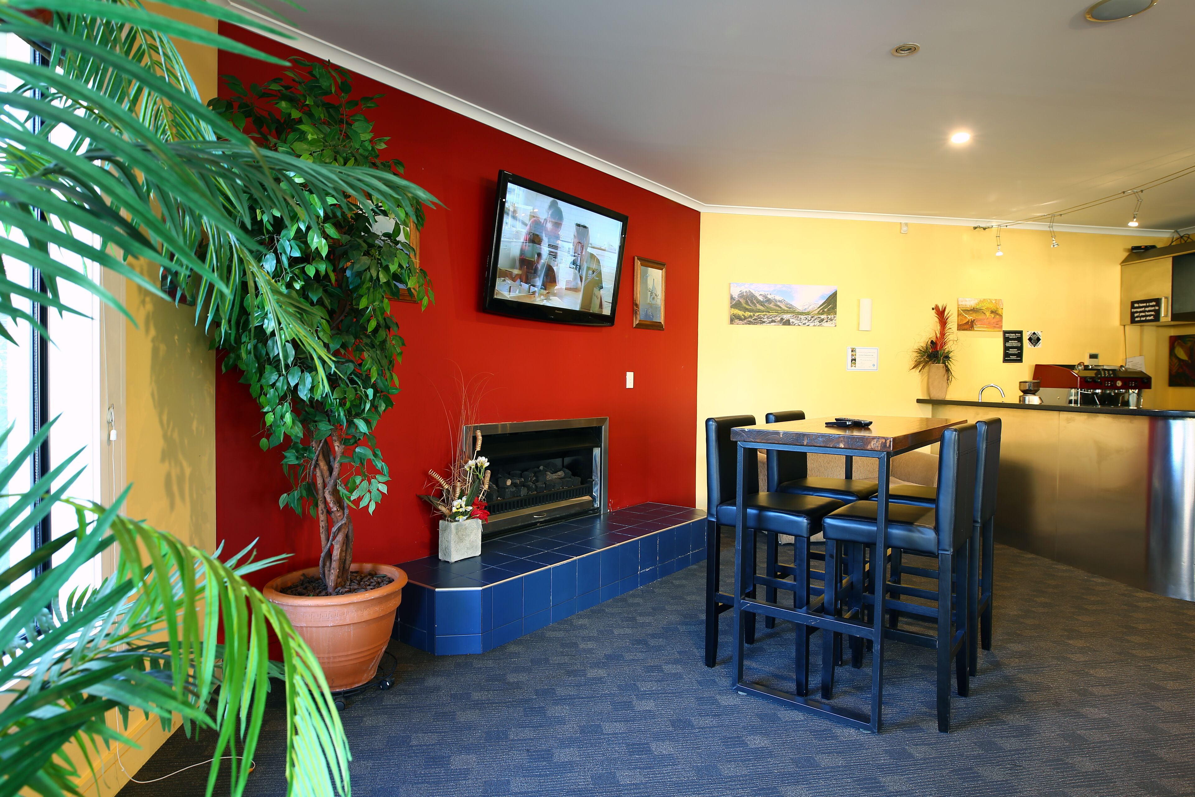 A living room with a fireplace, a dining area with chairs, and a kitchen in the background.