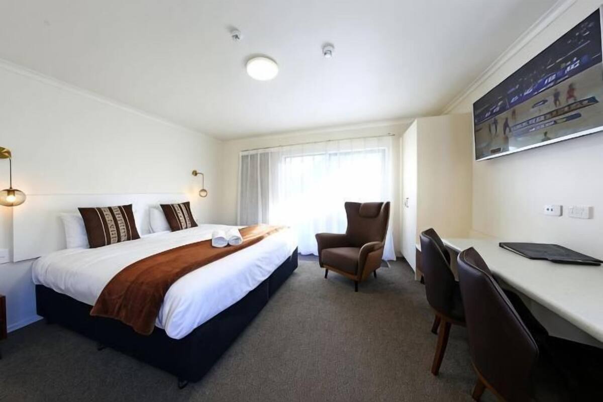 Ein Hotelzimmer mit Bett, Schreibtisch, Stuhl und Fernseher.