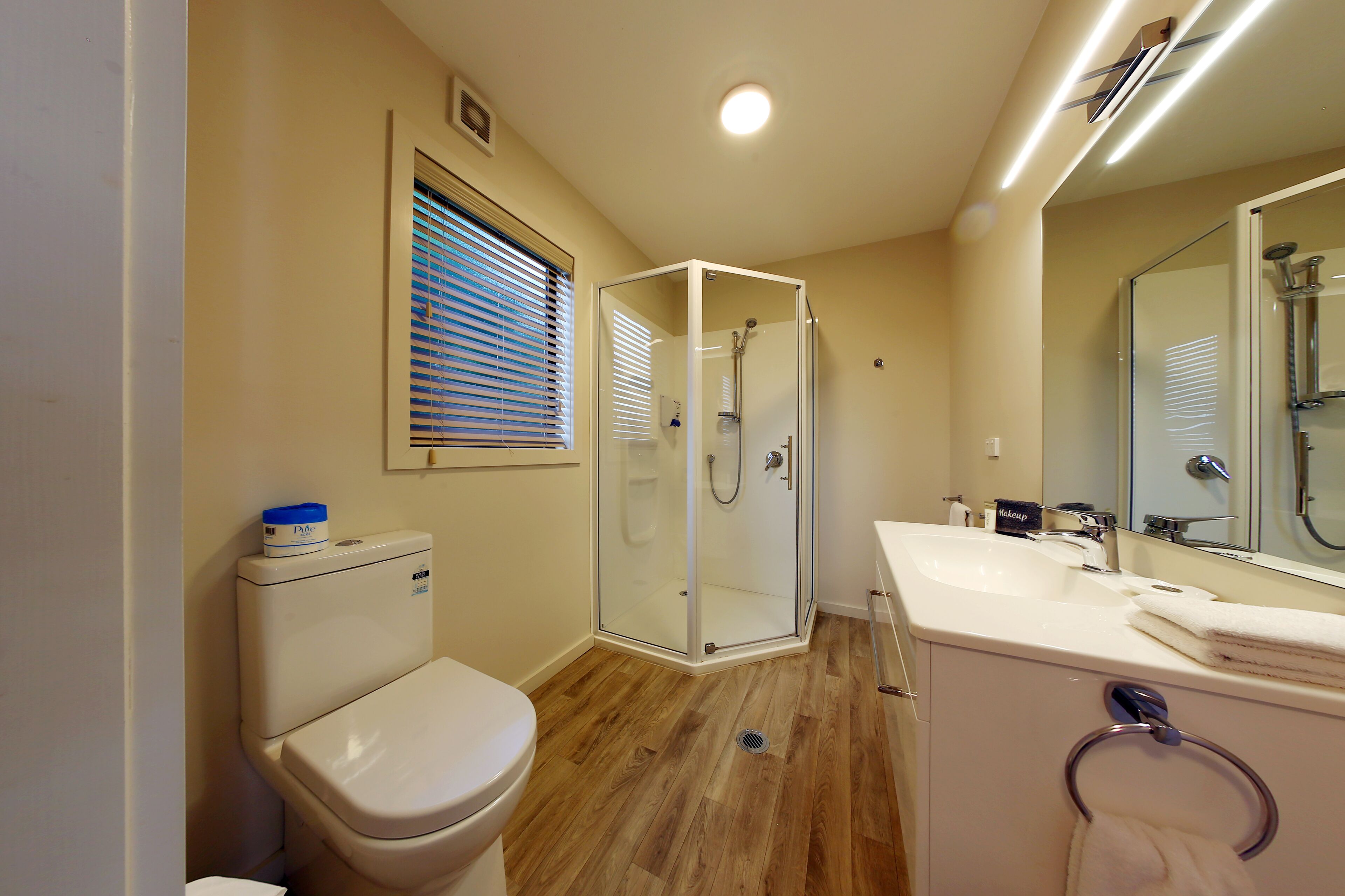 A bathroom with a toilet, a glass-enclosed shower, a sink, and a mirror.