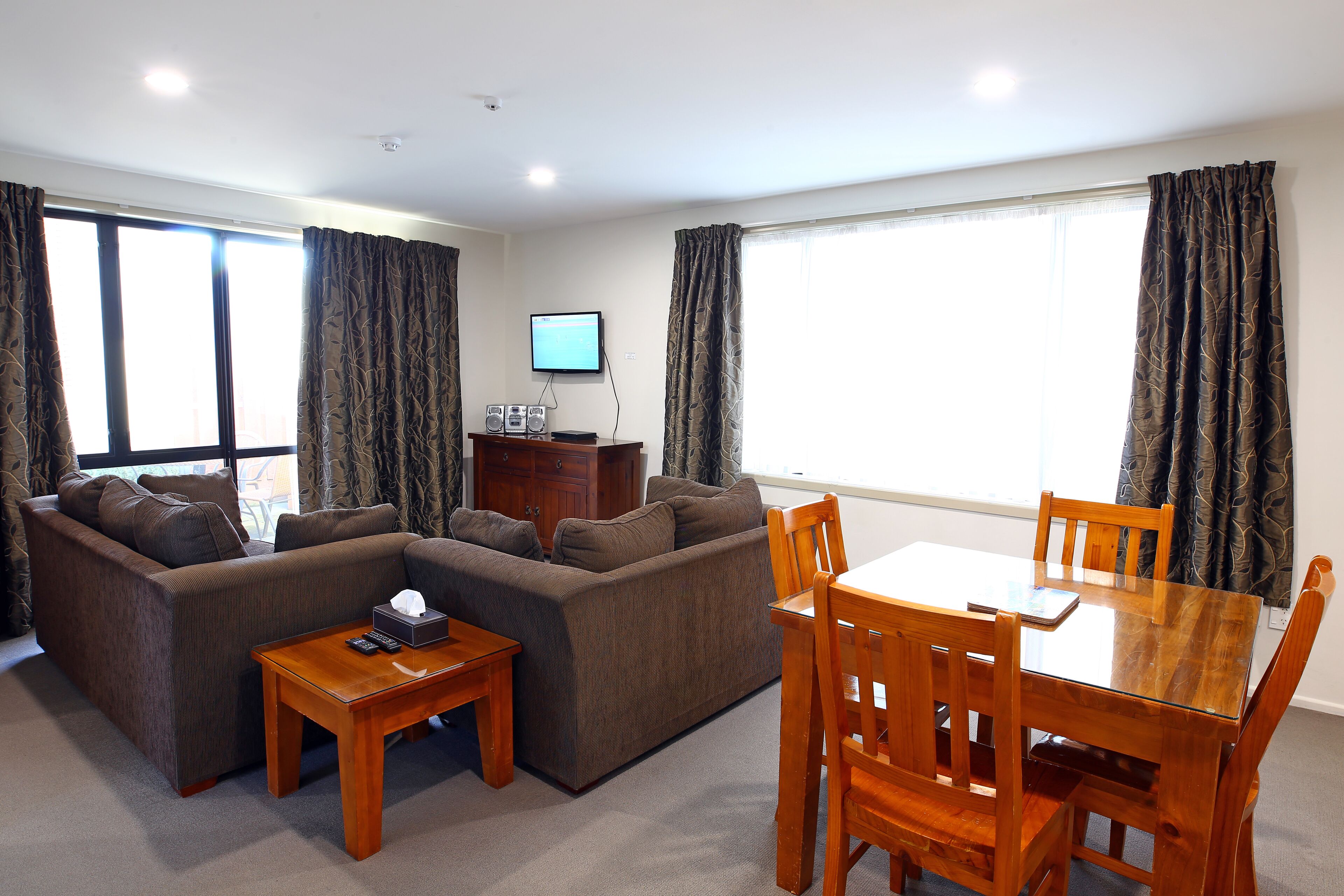 A living room with a sofa, a wooden coffee table, a TV, and a dining table with chairs.