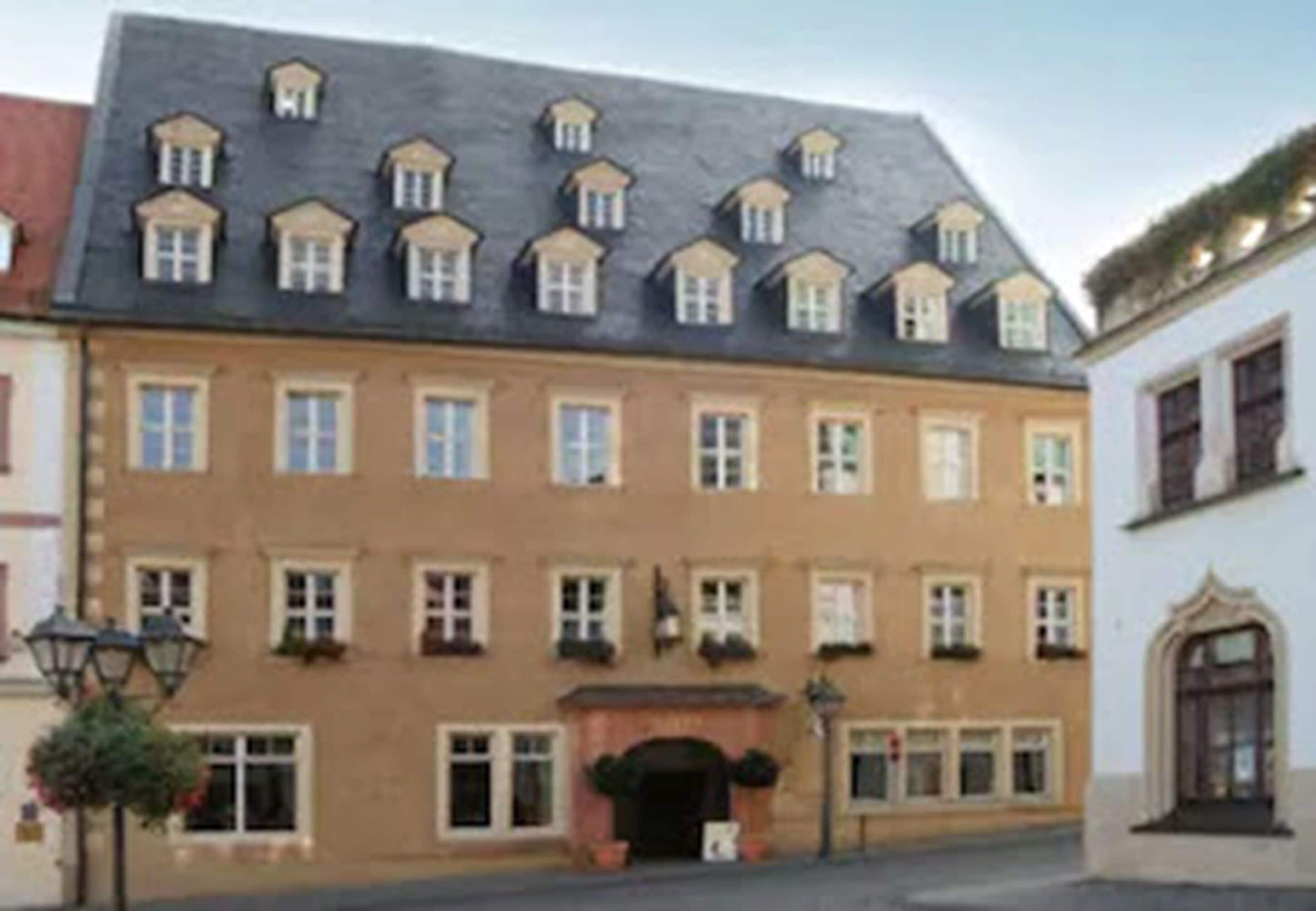 A multi-story building with a symmetrical facade, evenly spaced windows, and a central entrance with a dark archway.