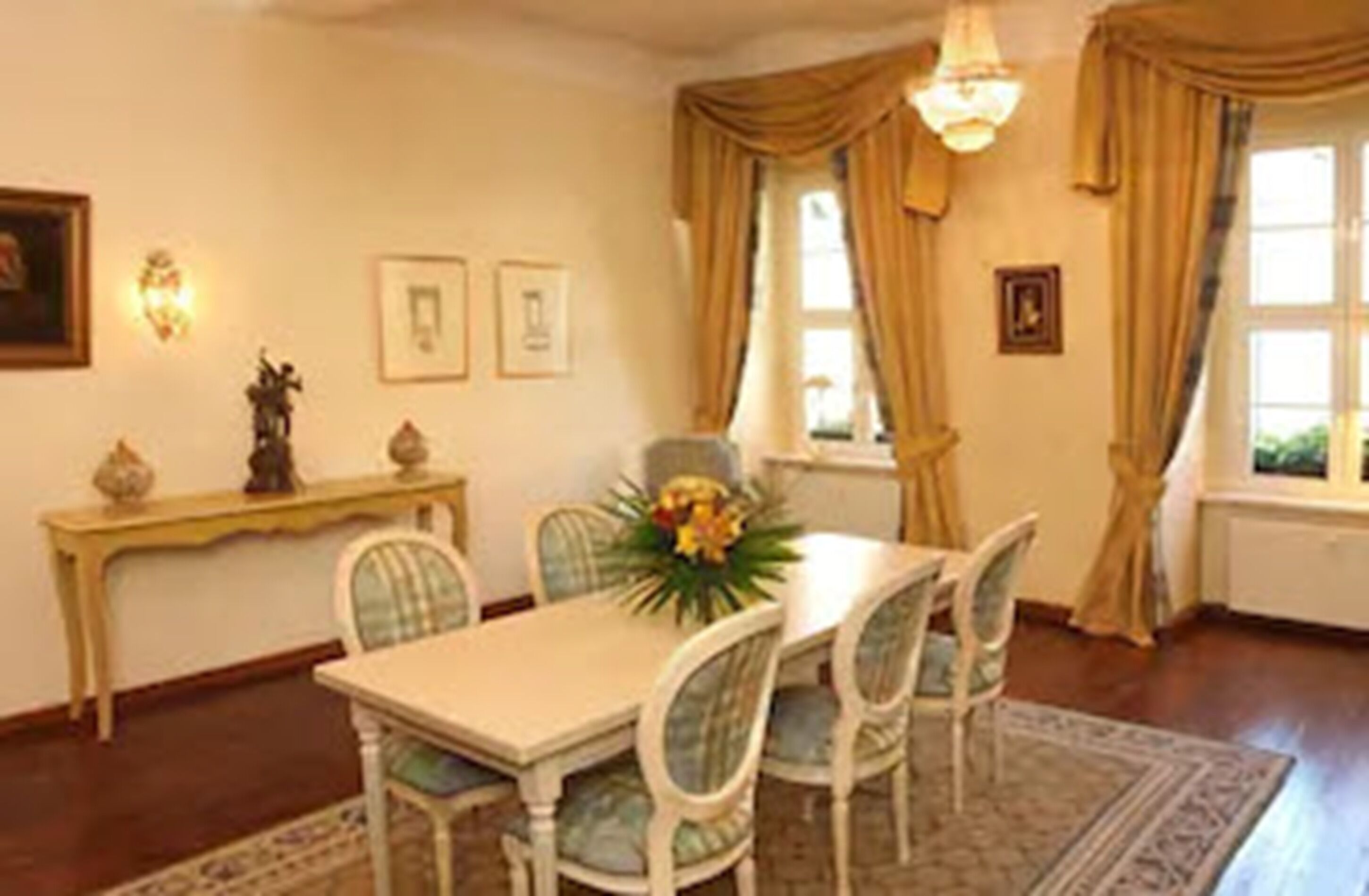 Un coin repas avec une table dressée pour quatre personnes, entourée de chaises, une petite console orn ée d’objets décoratifs et une fenêtre avec des rideaux.