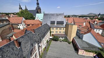 A courtyard surrounded by buildings with red-tiled roofs and a prominent church with two spires in the background.