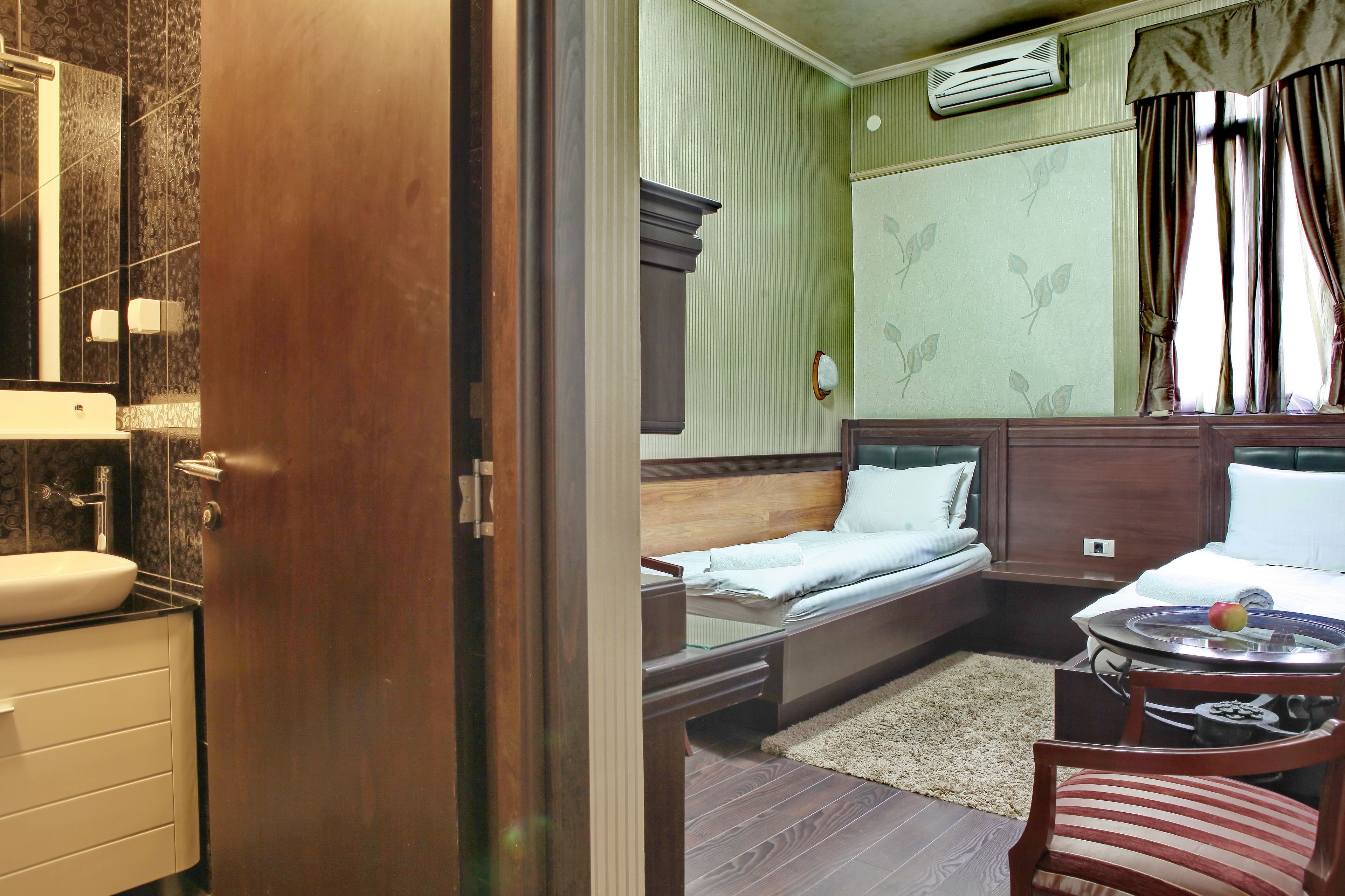 Una habitación de hotel pequeña con baño, una cama, una mesita con bandeja y una silla.