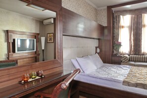 A hotel room with a bed, a desk with a glass top, a television, and a mirror. - Vila Terazije (Belgrade)