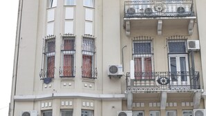 Un edificio de varios pisos con balcones, unidades de aire acondicionado y un escaparate con señalización.