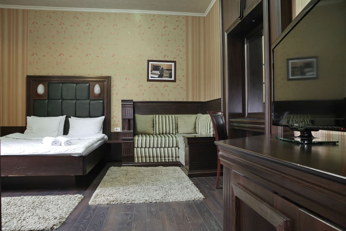 Una habitación de hotel con una cama grande, un sofá, un televisor y un escritorio.