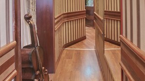 Un pasillo con pisos de madera, paredes a rayas y un espejo que refleja las luces del techo.