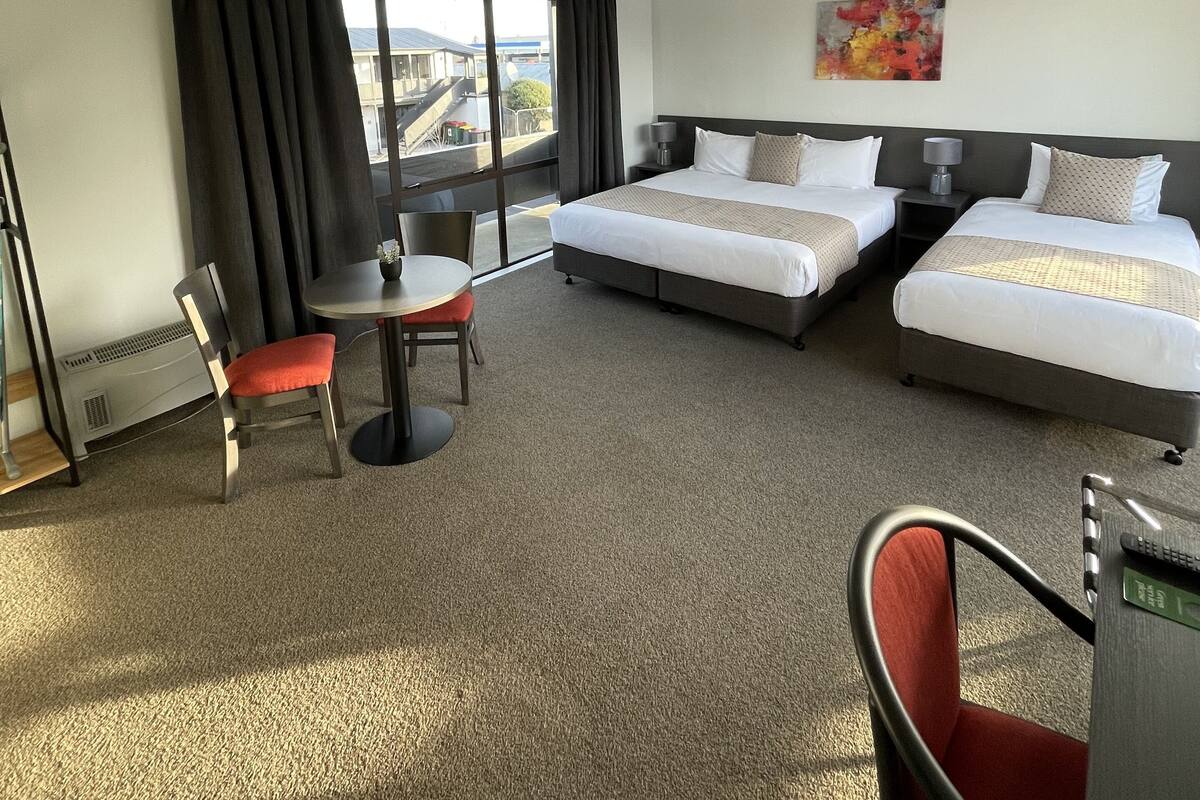 Hotellihuone, jossa on kaksi sänkyä, ruokapöytä ja tuoli.