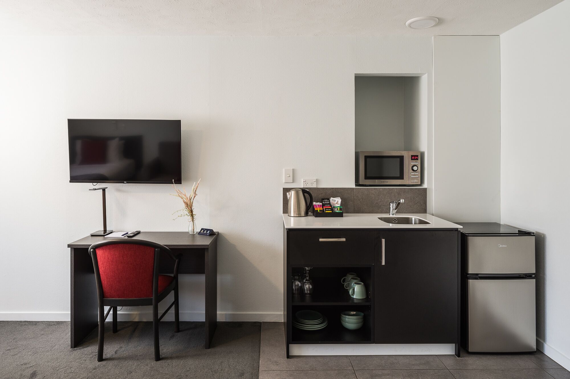 A compact kitchenette with a microwave, a sink, and a refrigerator.