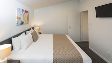 Hotelkamer met een bed, een aan de muur bevestigde televisie, een deur naar een andere kamer en een schilderij.
