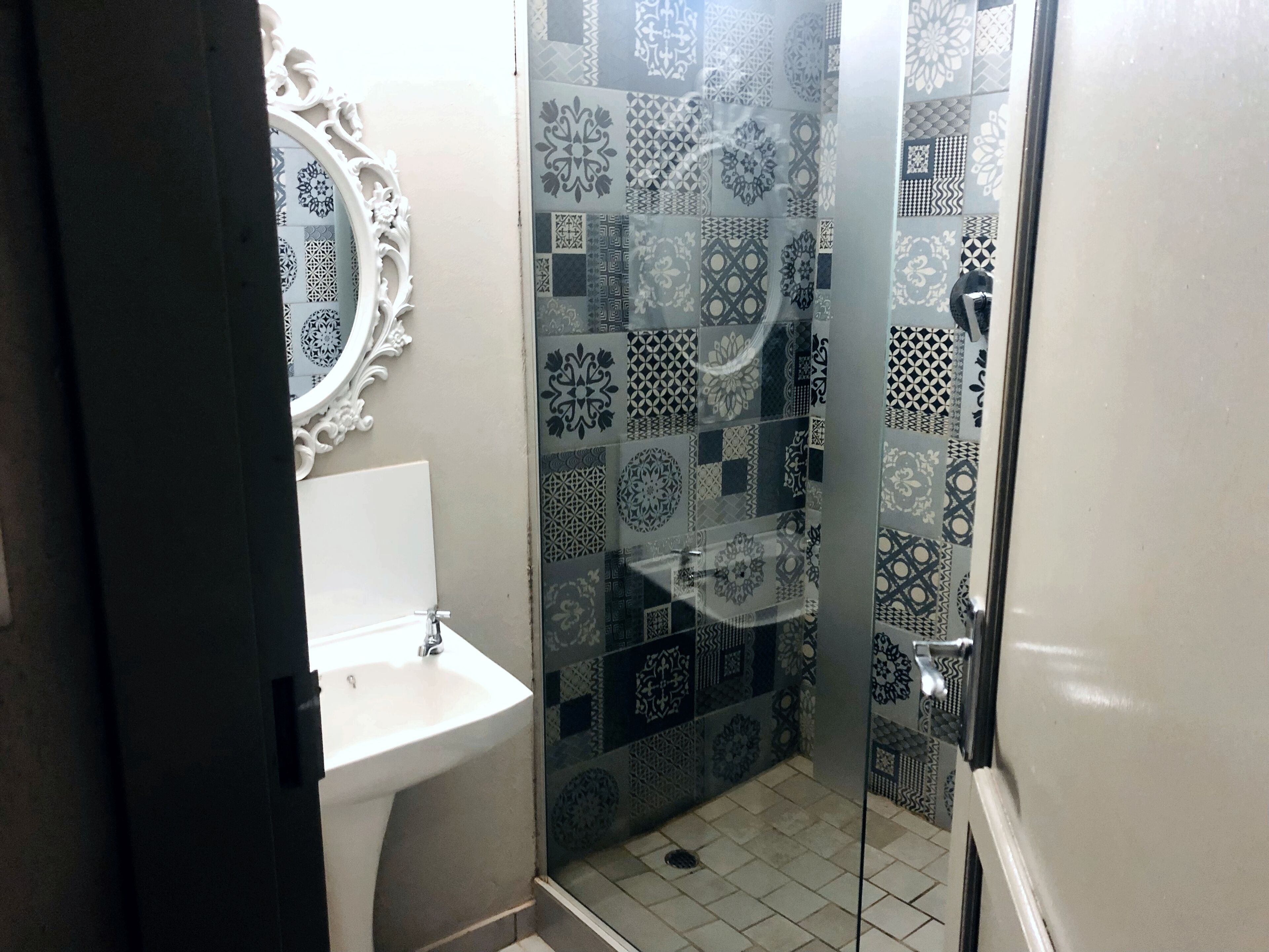 Un baño con lavamanos, espejo y baldosas con diseño.