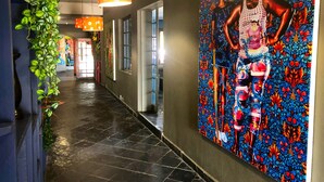 Un couloir orné d’une fresque murale, agrémenté de plantes en pot et éclairé par des suspensions.