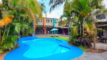 Una piscina al aire libre, sombrillas, sillones reclinables de piscina