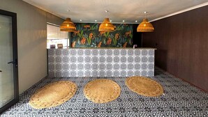 Un hall d’entrée avec un sol à motifs, un comptoir de réception et trois lampes suspendues.