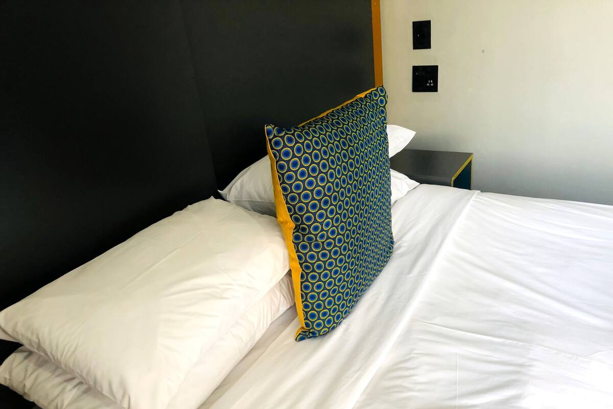 Un lit bien fait, avec du linge de lit blanc et un coussin à motifs.