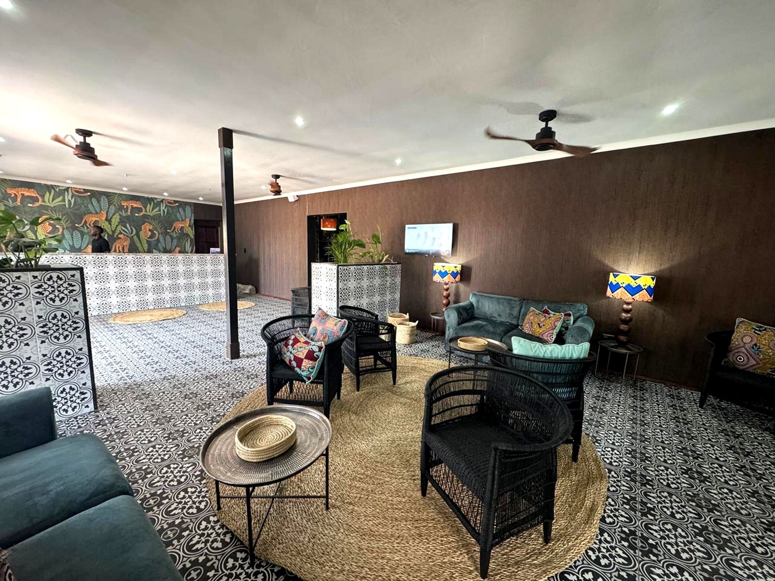 Un salón amplio con suelo estampado, un sofá, dos sillones, una mesa de centro y un televisor.
