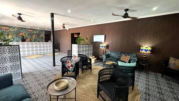 Un salón amplio con suelo estampado, un sofá, dos sillones, una mesa de centro y un televisor.