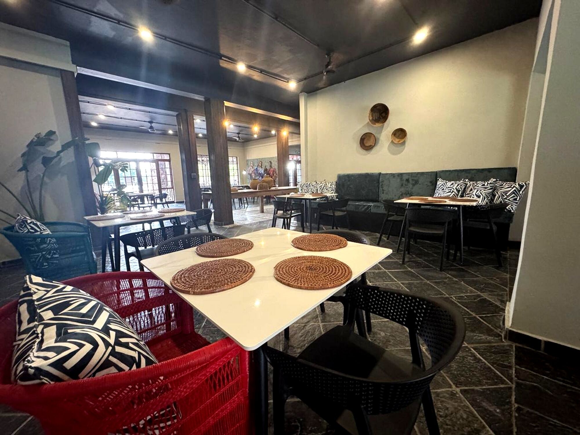 Un restaurante con mesas, sillas, una cesta roja y una silla negra.