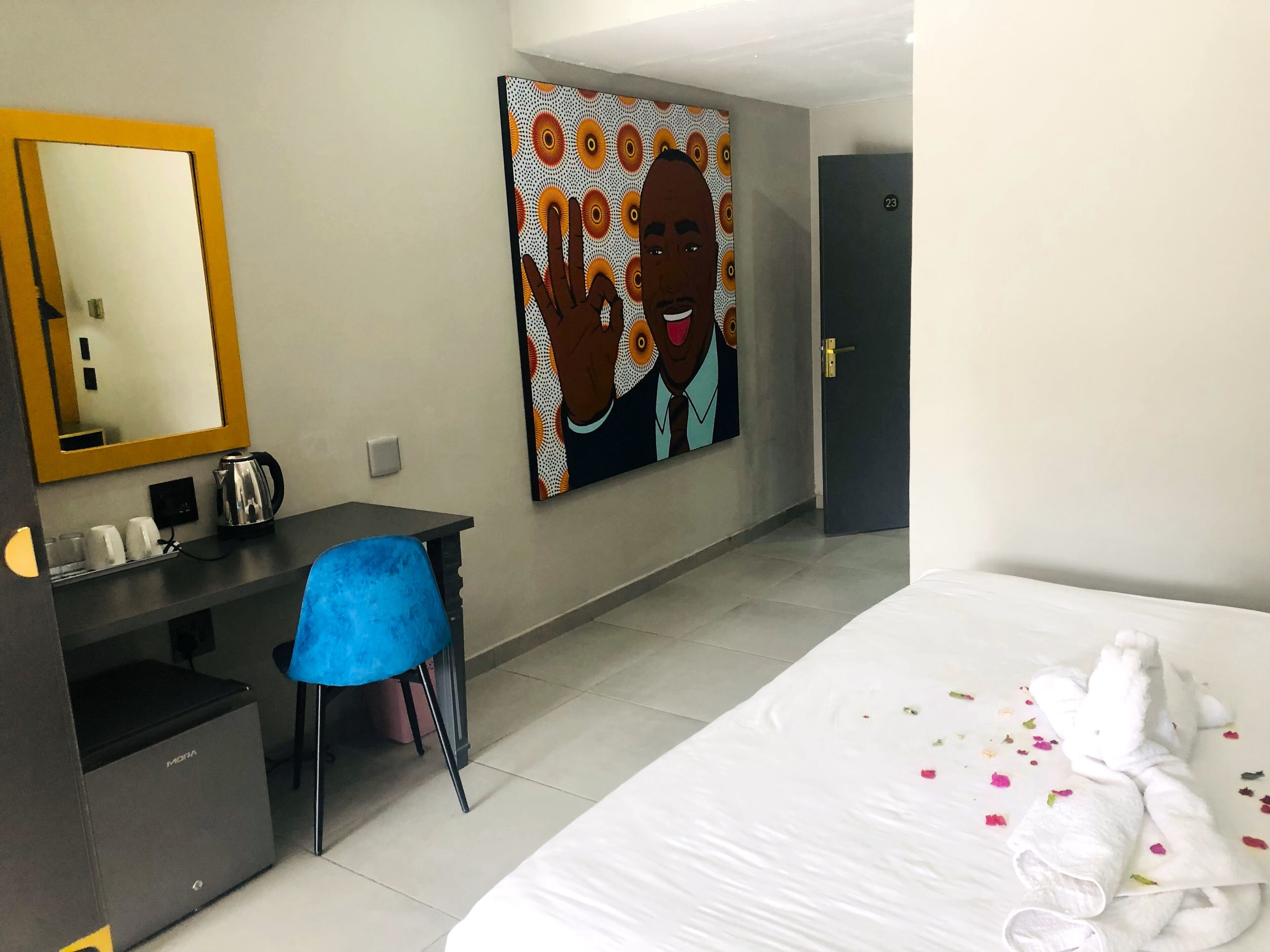 Ein Hotelzimmer mit Bett, Schreibtisch, Stuhl, Kaffeemaschine, Spiegel und einem Bild an der Wand.