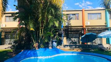 Una piscina al aire libre, sombrillas, sillones reclinables de piscina