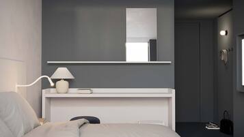 Un dormitorio moderno con cama, lámpara de noche y un espejo sobre una consola blanca.