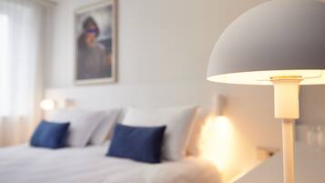 A bed with white bedding and blue pillows, a bedside lamp, and a framed picture on the wall.