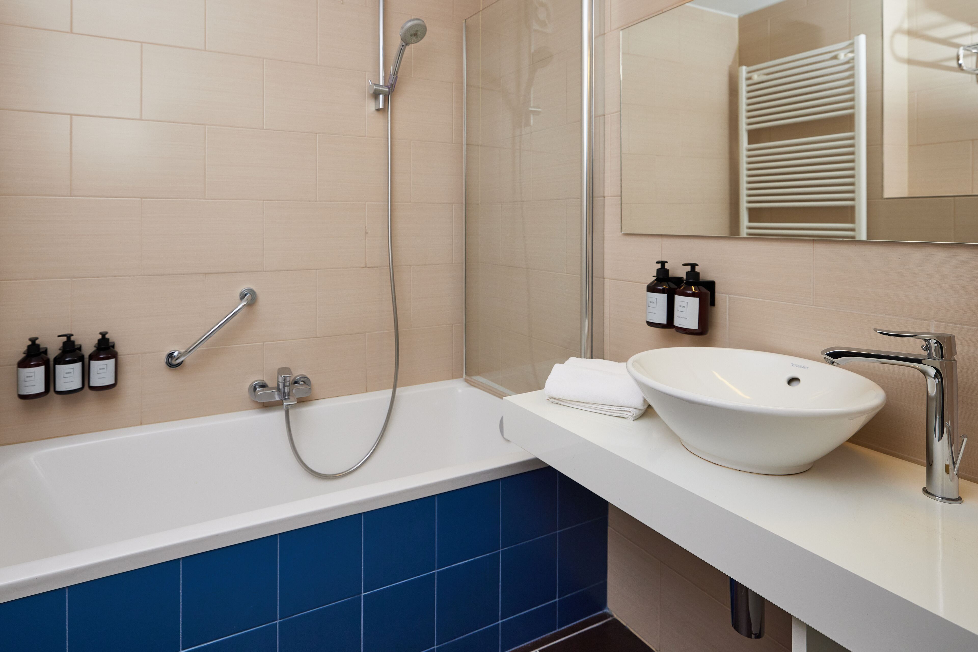 Un baño moderno con bañera, lavamanos blanco y cabina de ducha de vidrio.