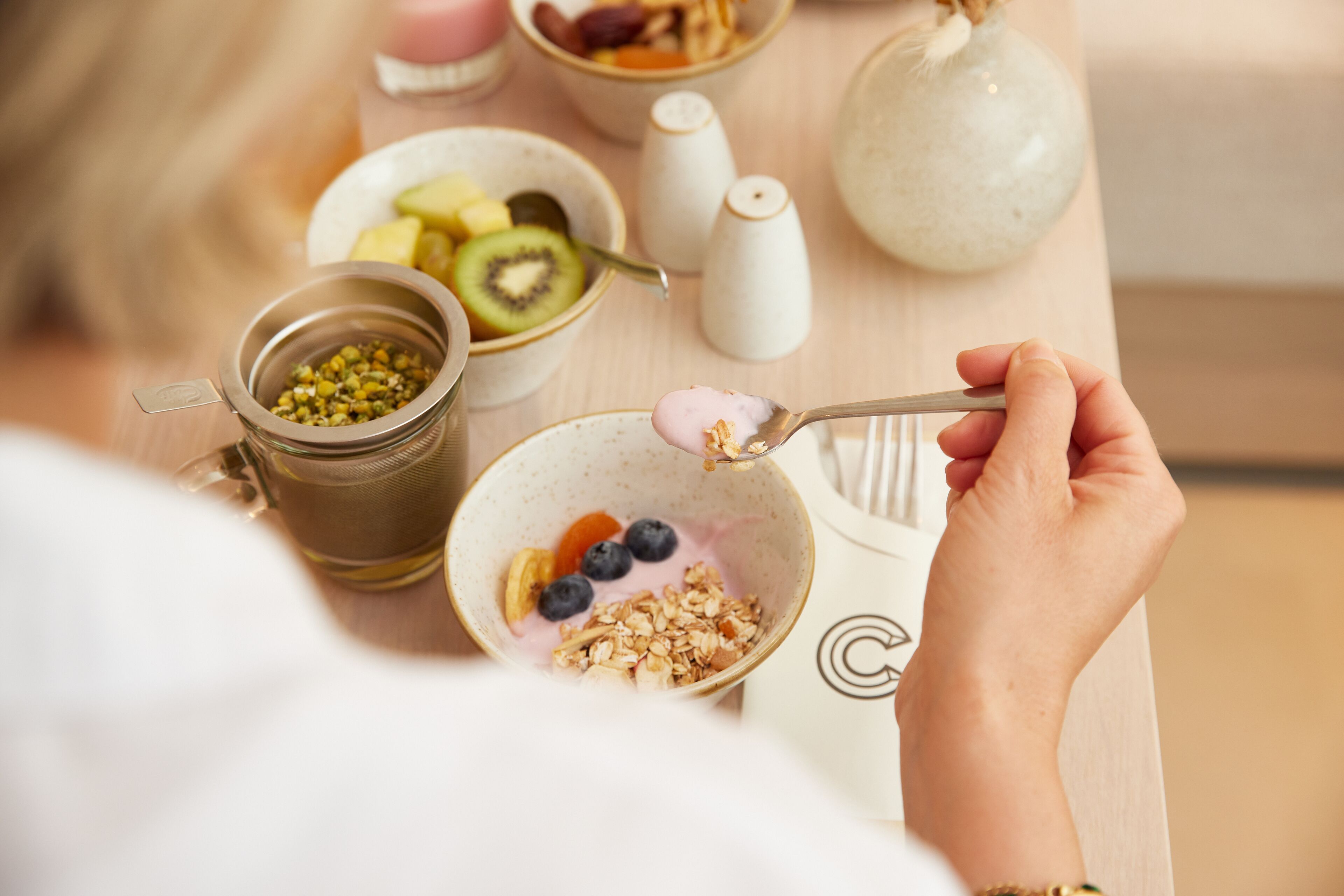 Une table mise pour le petit-déjeuner avec un bol de céréales, des myrtilles et une cuillère.