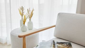 Un salon moderne avec un fauteuil rond de couleur claire, des accoudoirs en bois et un magazine posé sur l’assise.