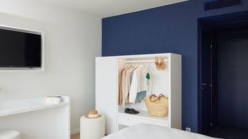 A bedroom with a bed, a wardrobe, a desk, and a television.