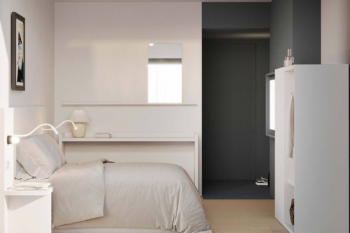 Un dormitorio moderno con cama, mesita de noche, lámpara y armario.