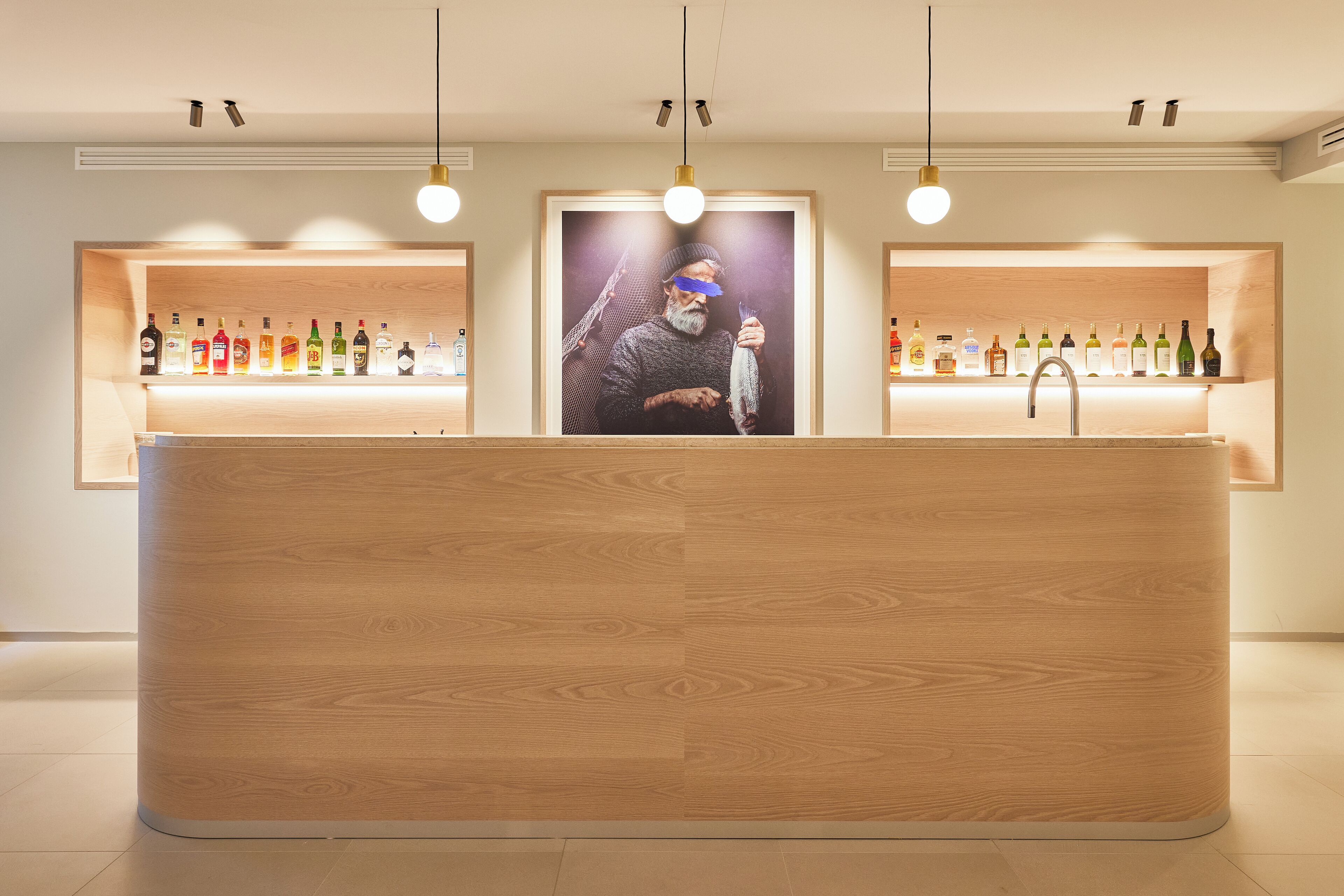 Un espace d’accueil avec un comptoir en bois, des étagères remplies de différentes bouteilles et un tableau encadré au-dessus du comptoir.