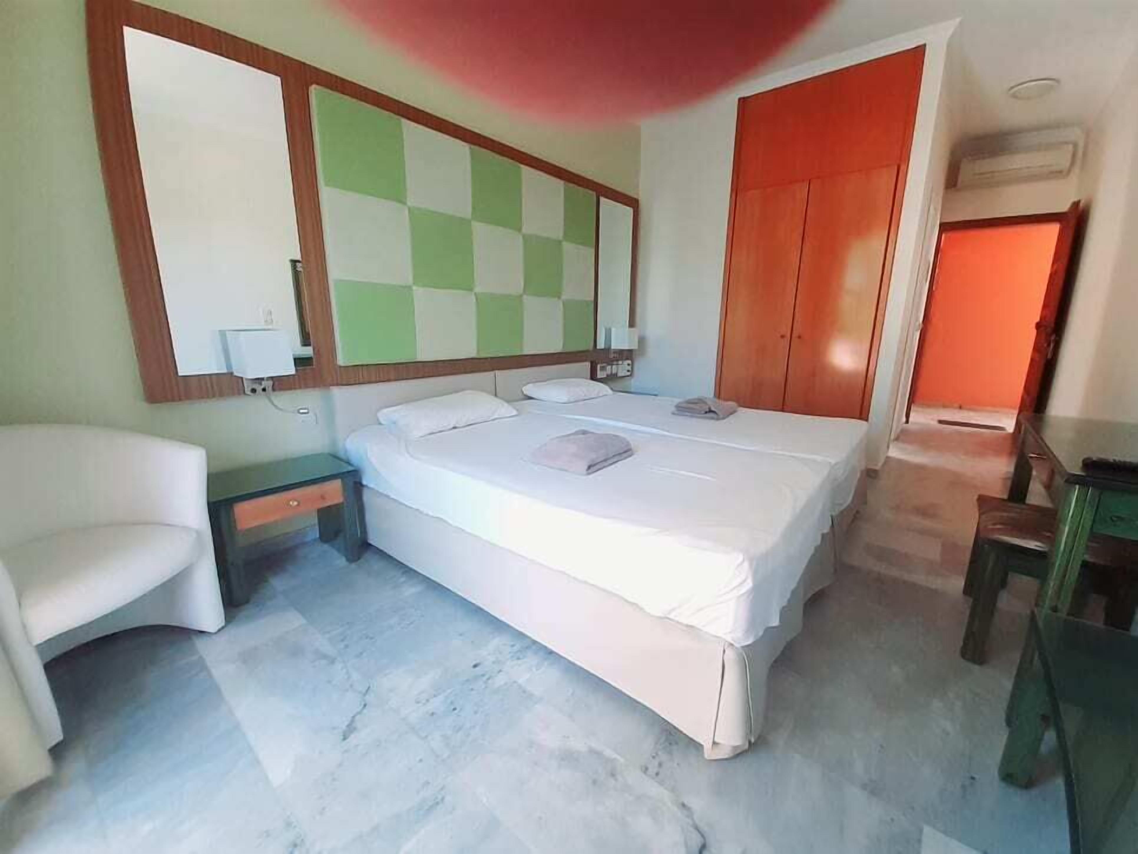 A bedroom with a large bed, a chair, a desk, and a wardrobe.