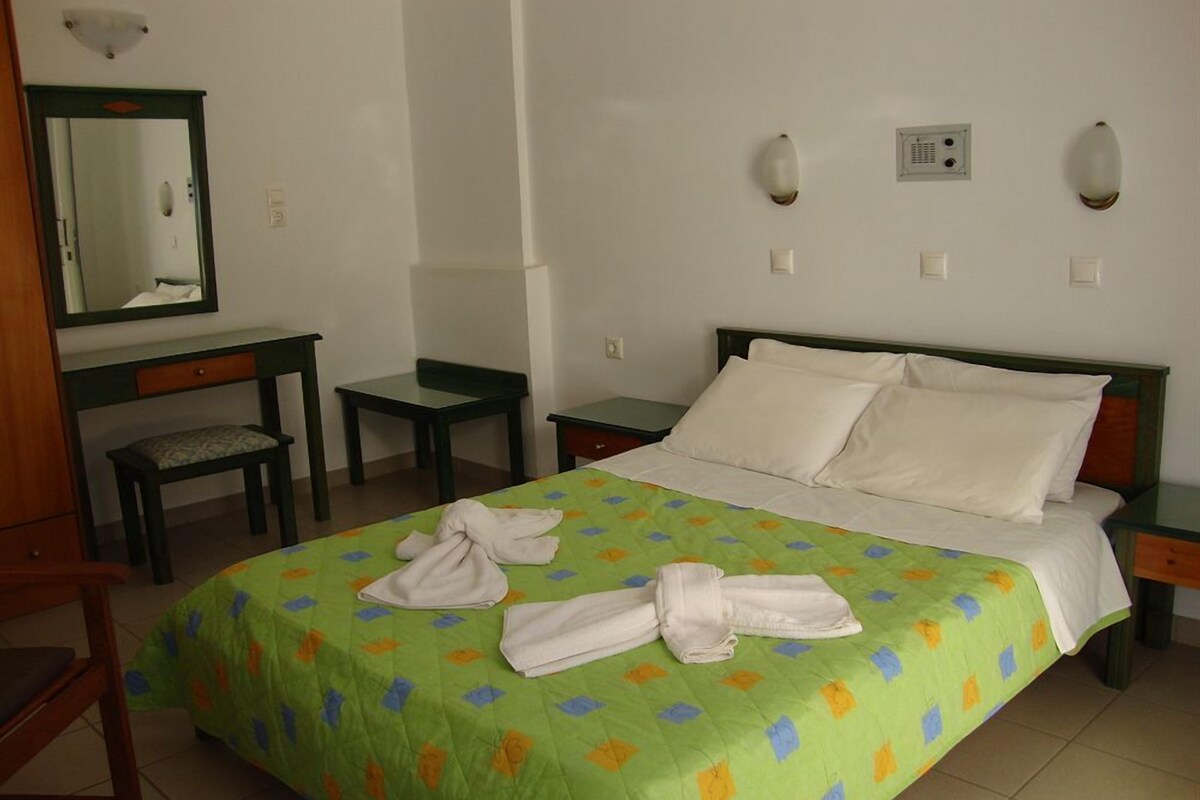 Una habitación de hotel con cama, escritorio, silla y espejo.