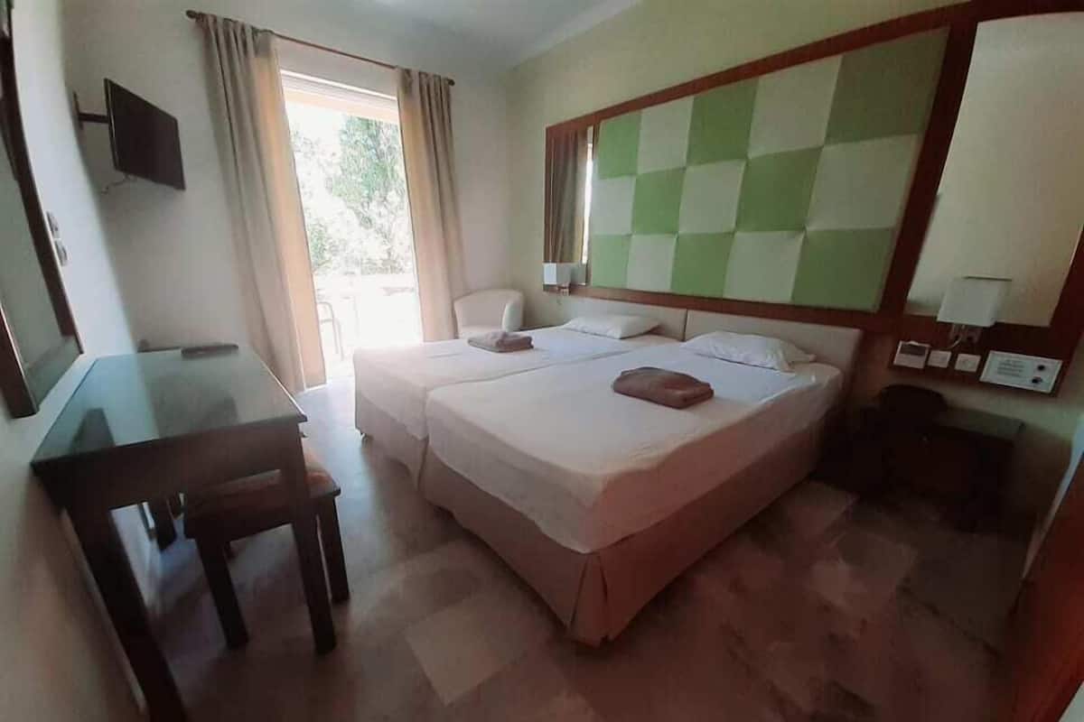 A hotel room with a bed, a desk, and a television.