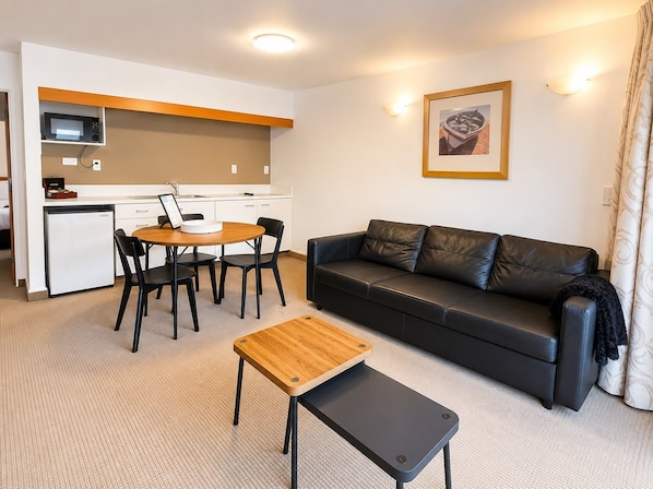 Un espacio habitable compacto con kitchenette, comedor, sofá y una pequeña mesa.